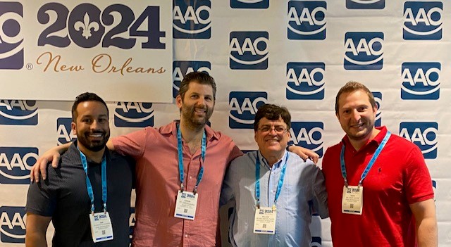 Four people pose for a photo. Text on background reads "2024 New Orleans" and features "AAO" logo. 