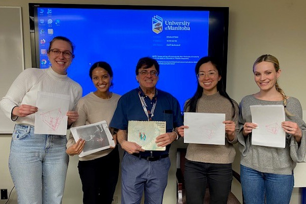 Five people pose for photo. They each hold a piece of paper. 