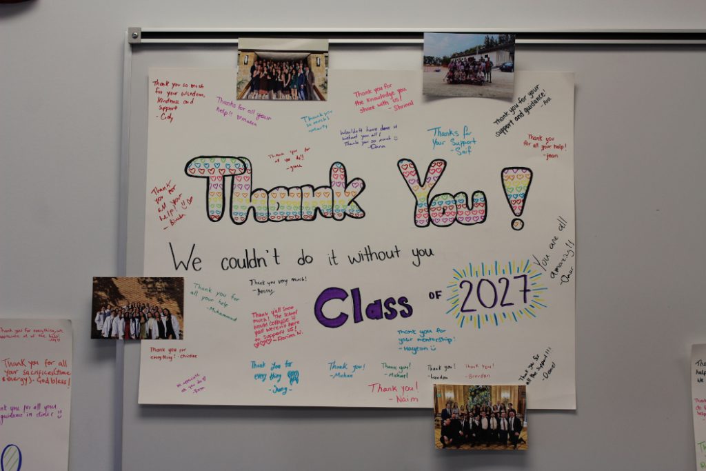 Main text reads: "Thank you! We couldn't do it without you. Class of 2027." Four photos of the class are stuck to the poster. The students signed names and included messages.