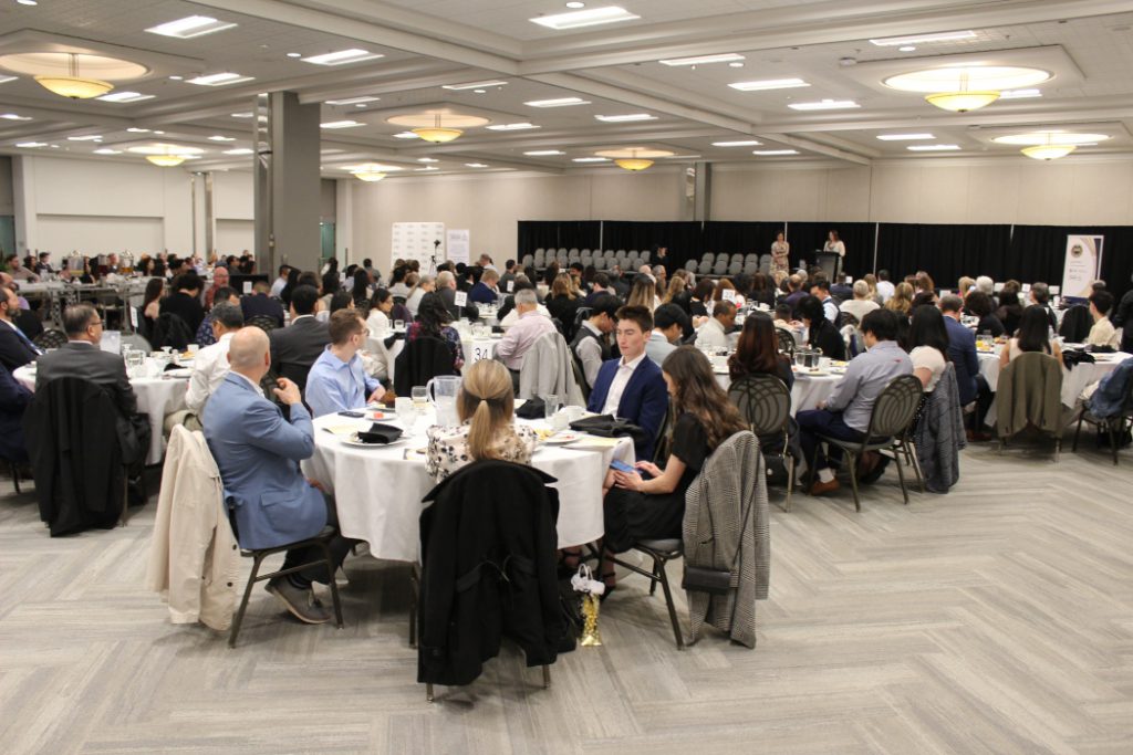 Large group of people sitting at round tables. 