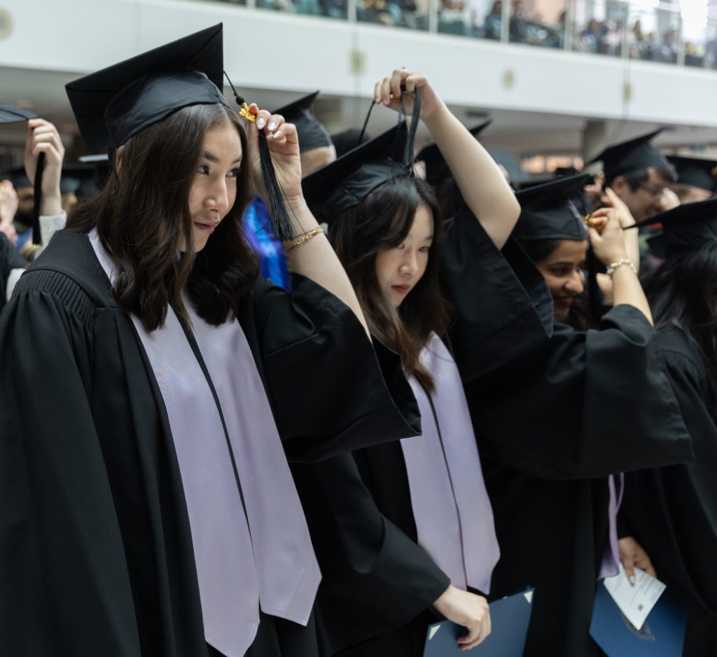 Three dental hygiene graduates move the tassels on their caps to the left side. 