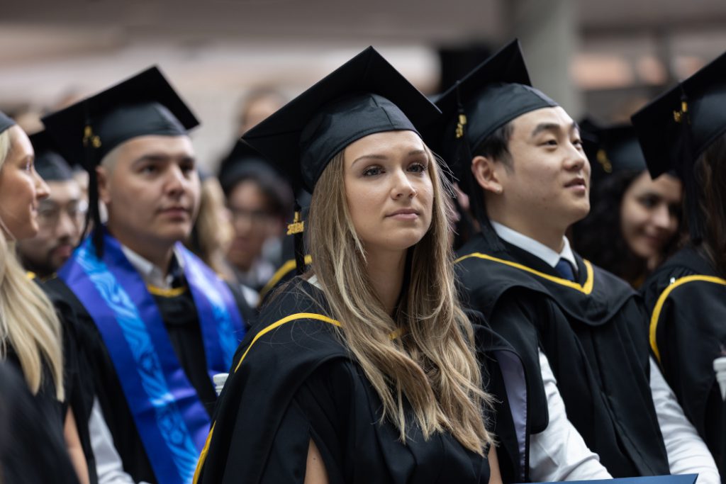 Four dentistry graduates wear caps and gowns. 