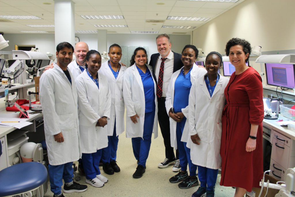 Seven students pose with Health Minister Mark Holland in a lab. 