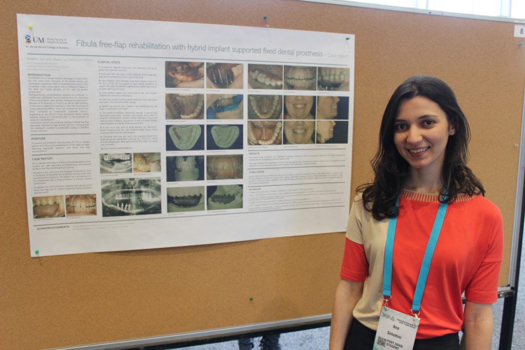 Ana Schettini stands in front of her poster posted on a bulletin board. 