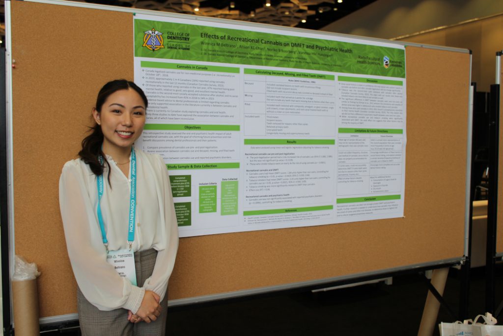 Winnica Beltrano stands in front of her poster posted on a bulletin board. 