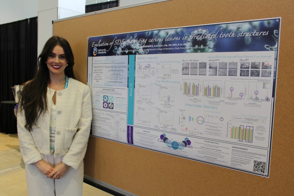 Larissa Bubnowicz stands in front of her poster posted on a bulletin board. 