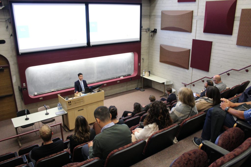 Person gives a presentation in front of an audience in a lecture theatre. 