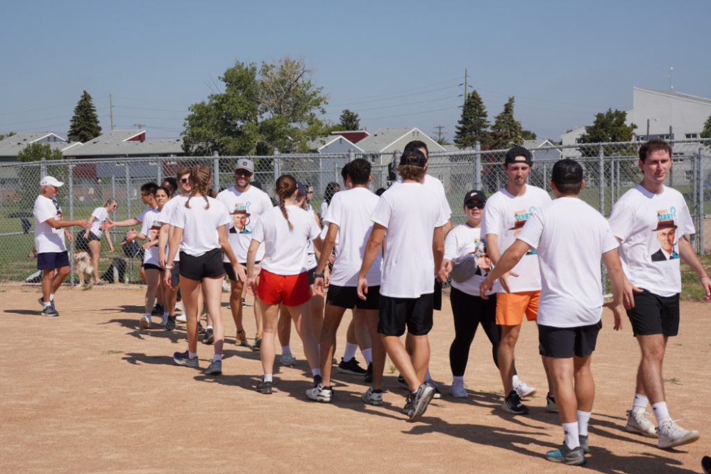 Two teams shake hands after a game of kickball. 