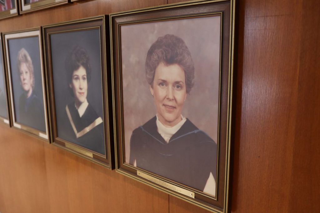 Framed photo of professor Marnie Forgay next to two other framed photos of previous directors. 