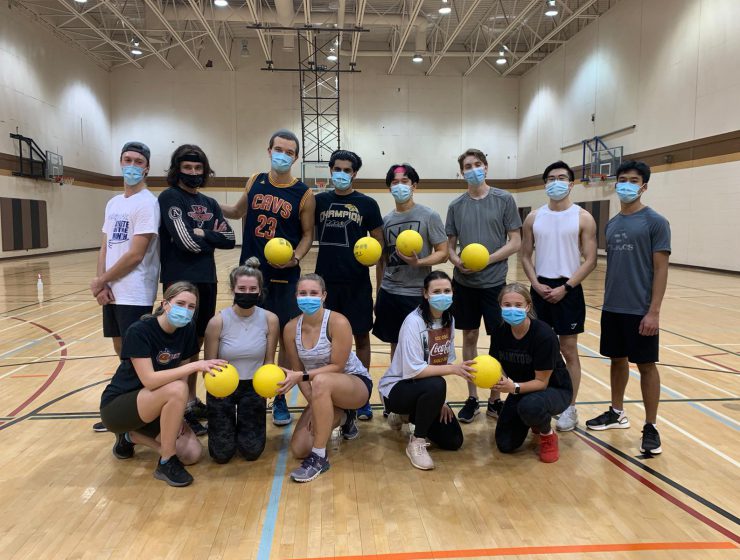 College of Pharmacy students pose for a group photo in a gym, some of the students are holding dodge balls.