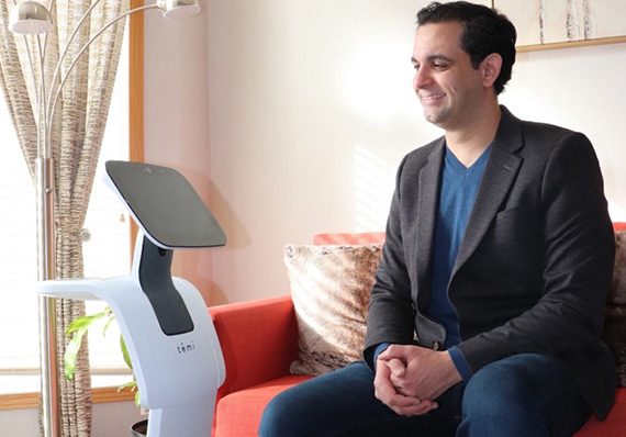 Dr. Amine Choukou sits with a telepresence robot.