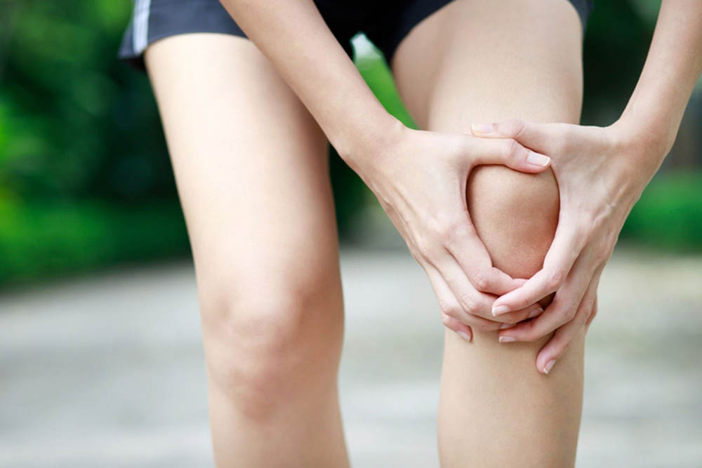 A person holds their sore knee.