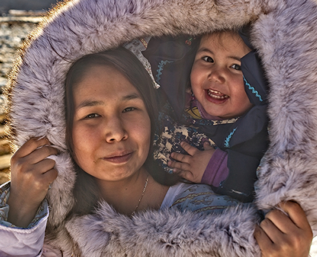 Inuit mother and daughter under a fur-lined hood.