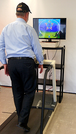 A man walks on a treadmill while looking at a computer screen.