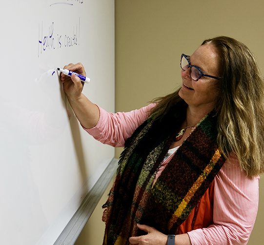Dr. Laura MacDonald writes on a whiteboard.
