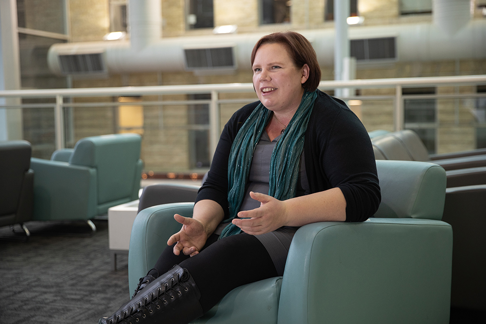 Lisa Engel sits on a chair in the Brodie Centre atrium while being interviewed.