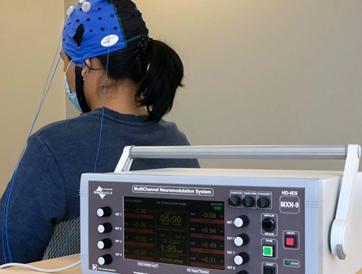 A student demonstrates how research participants will wear a cap to receive brain stimulation.