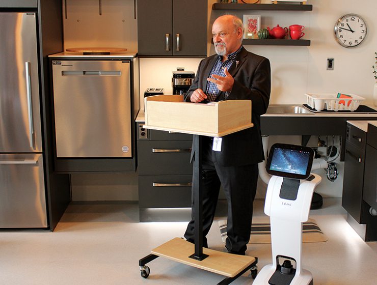 Dr. Reg Urbanowski, dean of the College of Rehabilitation Sciences, speaks at the opening of the smart suite, accompanied by a telepresence robot.