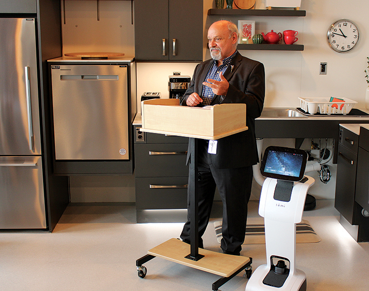 Dr. Reg Urbanowski, dean of the College of Rehabilitation Sciences, speaks at the opening of the smart suite, accompanied by a telepresence robot.
