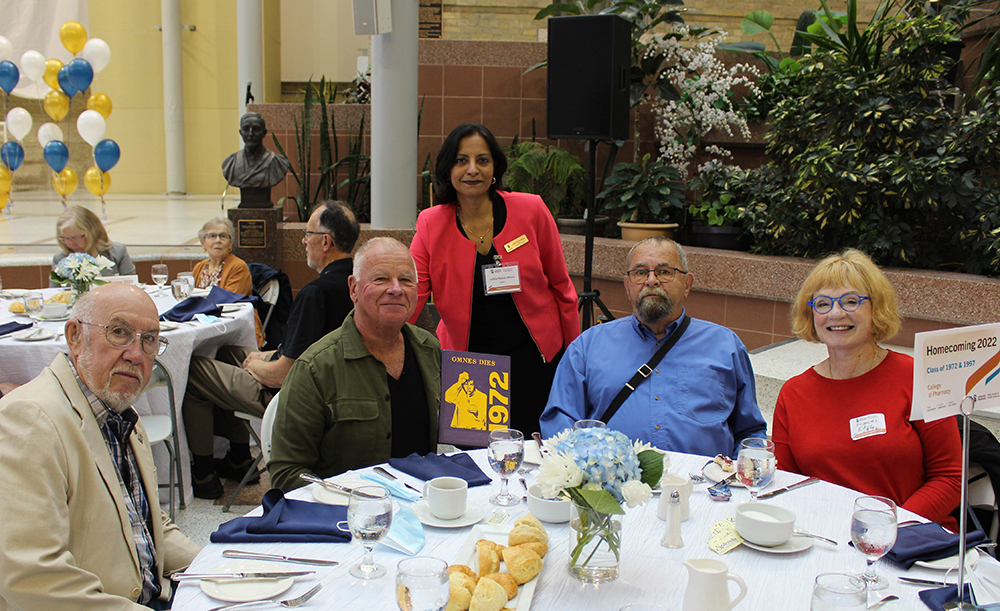 College of Pharmacy Dean Lalitha Raman-Wilms and four alumni from the Class of 1972 at a table at Homecoming.