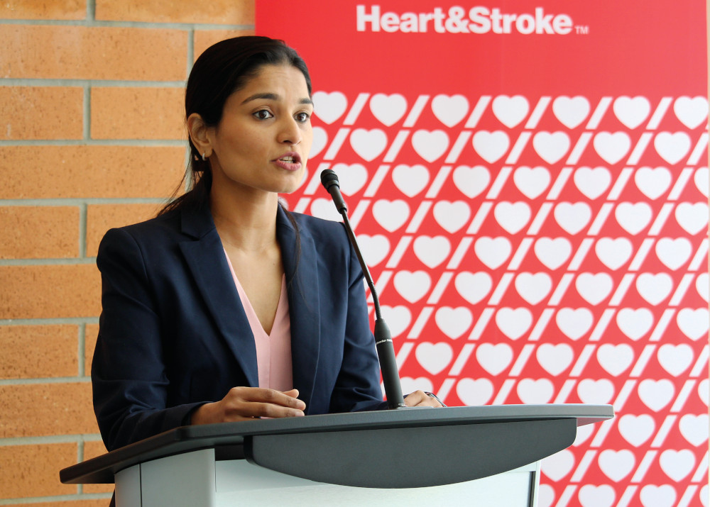 Dr. Nishita Singh speaks at a lectern. The Heart & Stroke logo is repeated behind her on a banner. The banner also reads "Heart & Stroke." 