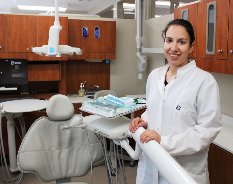 Dr. Chrysi Stavropoulou stands in a clinic next to a dental chair.