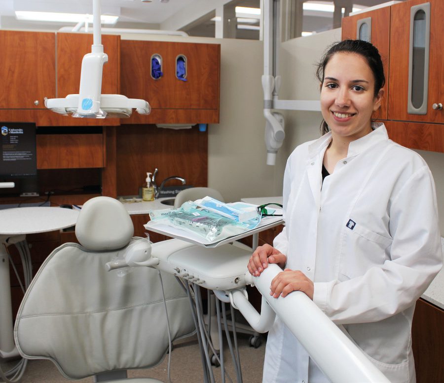 Dr. Chrysi Stavropoulou stands in a clinic next to a dental chair.