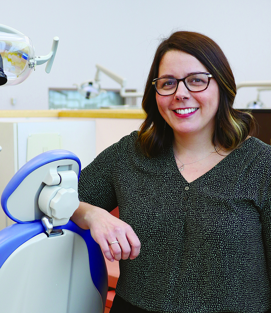 Kathy Yerex stands next to a dental chair.