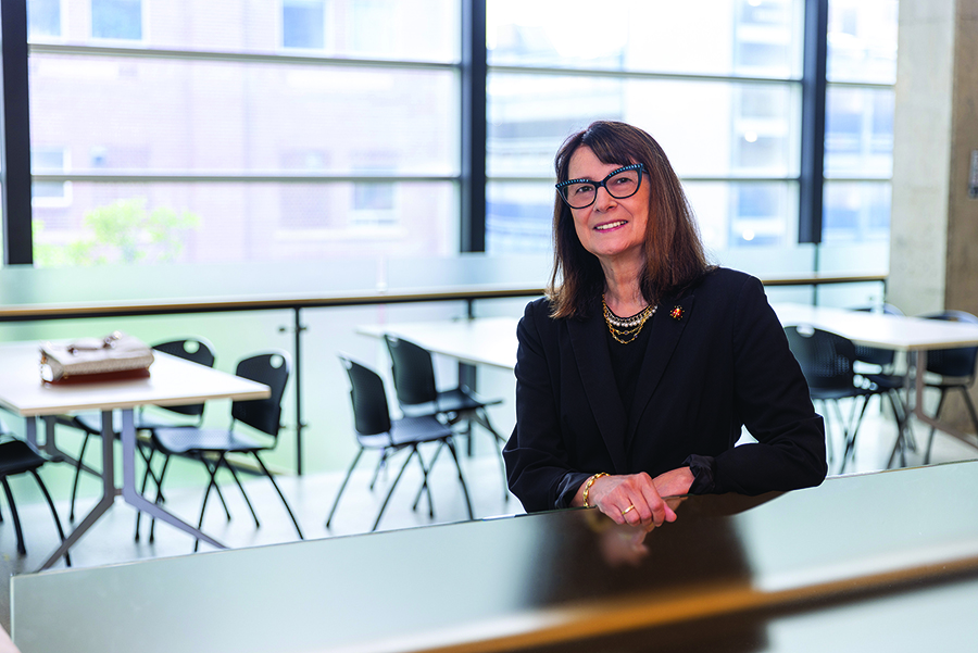 Dr.-Silvia-Alessi-Severini stands in a brightly lit room with several chairs and tables behind her, next to a large window.