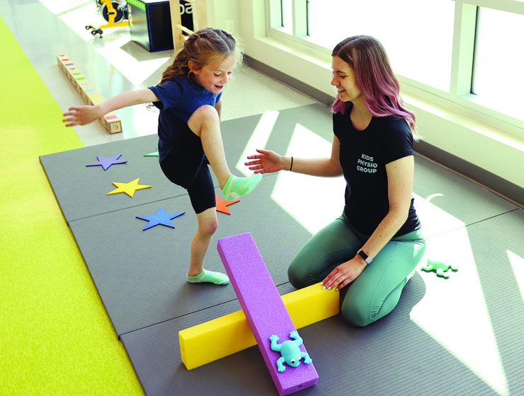 A physiotherapist works with a child in a bright, colourful room.