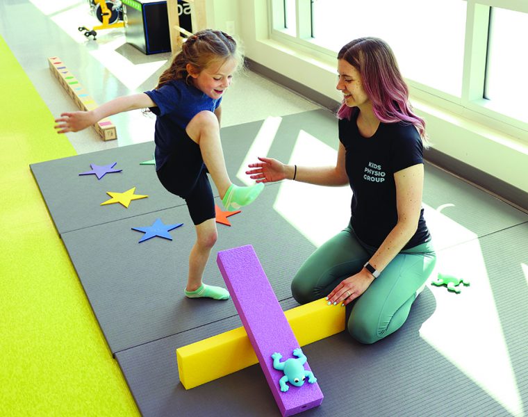 A physiotherapist works with a child in a bright, colourful room.