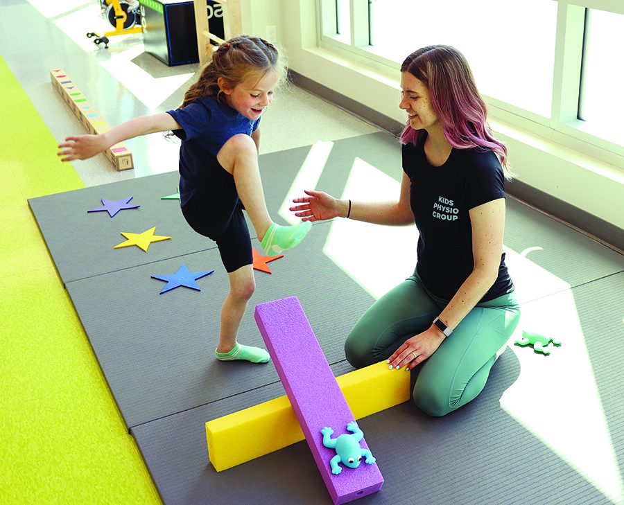 A physiotherapist works with a child in a bright, colourful room.