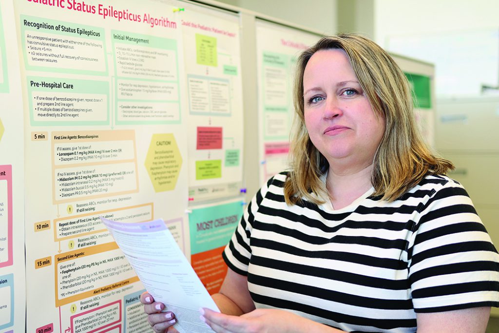 Lisa Knisley stands with a paper in front of a research poster.