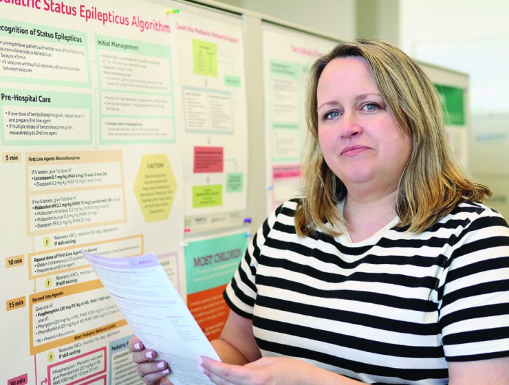 Lisa Knisley stands with a paper in front of a research poster.