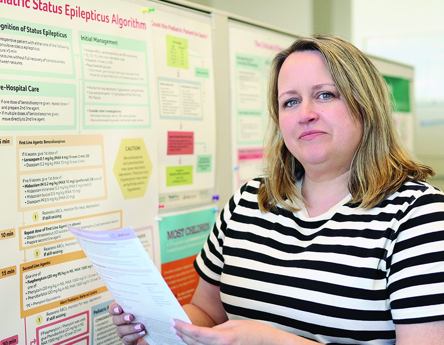 Lisa Knisley stands with a paper in front of a research poster.