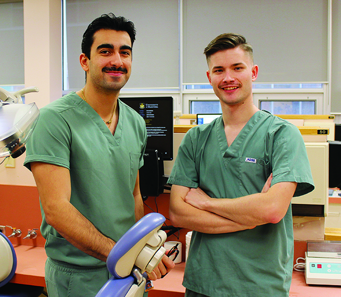 Amirali Paknahad and Quinn Boyko wearing scrubs in a dental clinic.