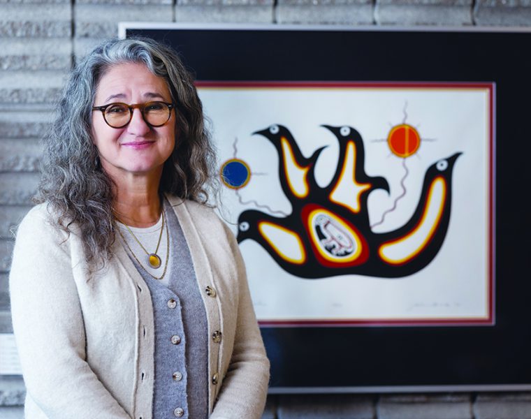 Dr. Moni Fricke with an artwork by Jackson Beardy from Garden Hill First Nation, one of the Island Lake communities where Fricke worked as a physiotherapist.