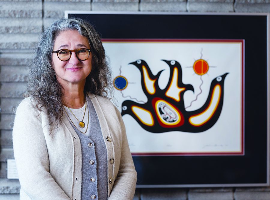 Dr. Moni Fricke with an artwork by Jackson Beardy from Garden Hill First Nation, one of the Island Lake communities where Fricke worked as a physiotherapist.