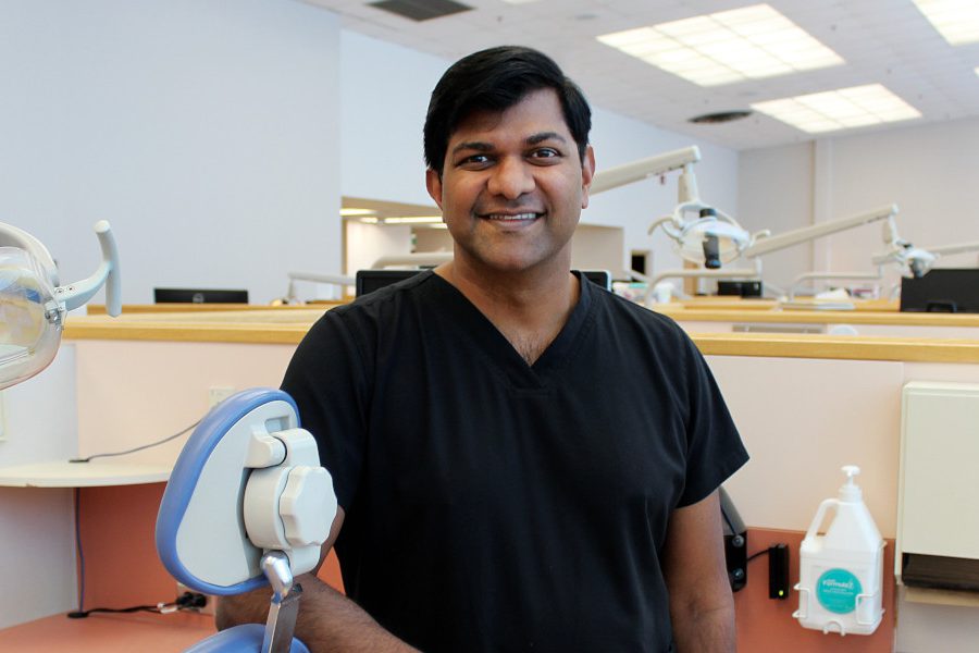 Portrait of Dr. Anil Menon in a dental clinic. He is leaning against a dental chair.