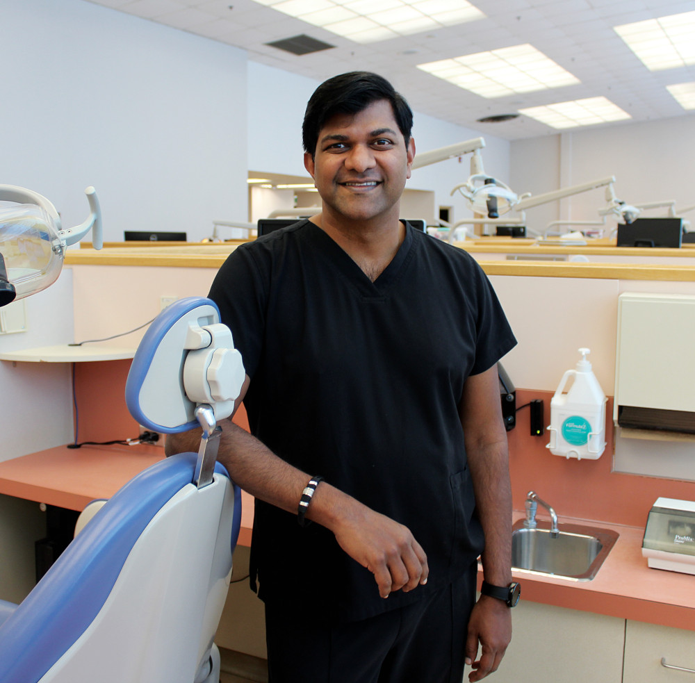 Portrait of Dr. Anil Menon in a dental clinic. He is leaning against a dental chair. 