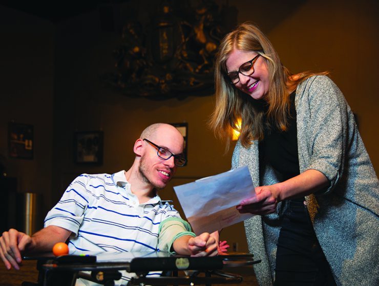 Actor Myles Taylor consulting with Stefanie Wiens in a theatre lobby.