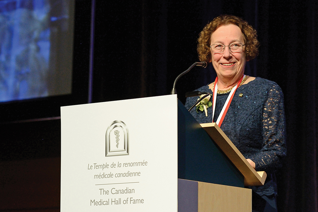 Estelle Simons speaks at a Canadian Medical Hall of Fame podium.