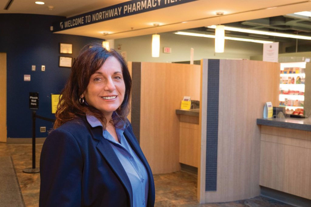 Gayle Romanetz smiles at the camera in a pharmacy.