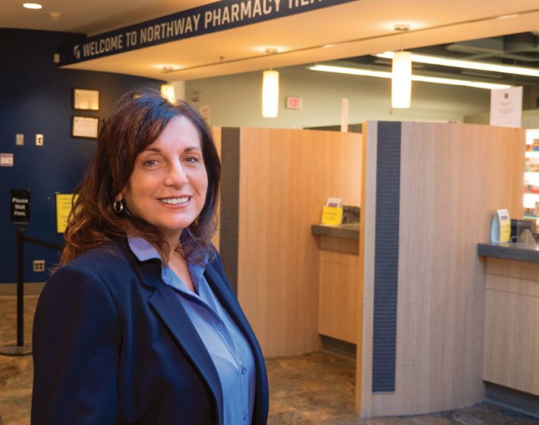 Gayle Romanetz smiles at the camera in a pharmacy.