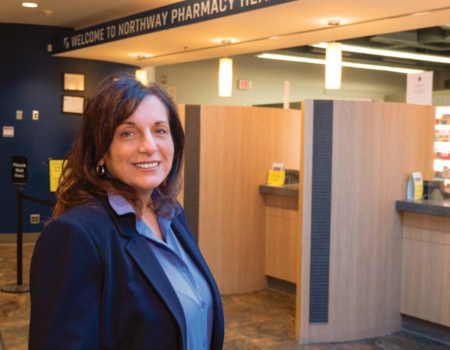 Gayle Romanetz smiles at the camera in a pharmacy.